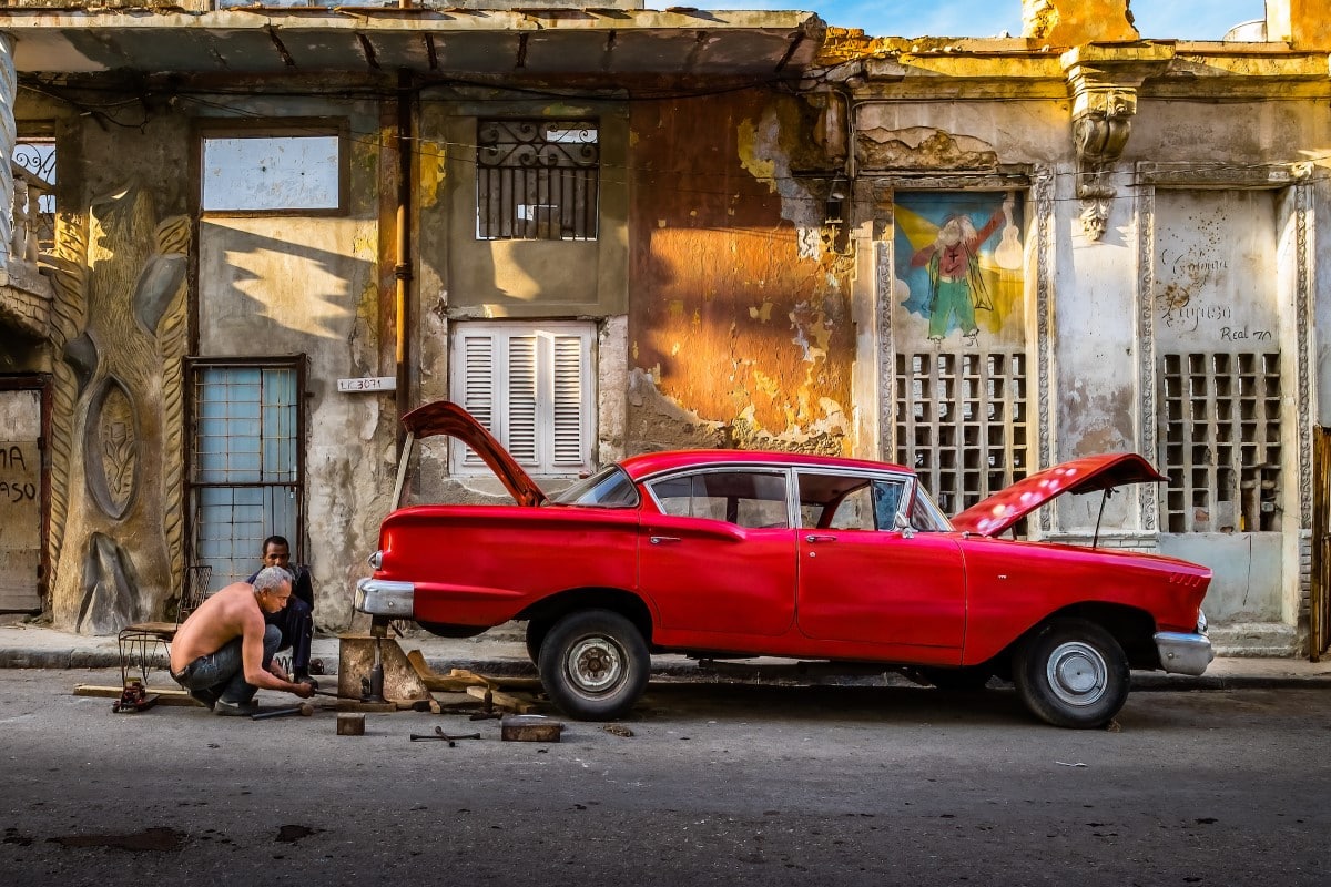 Mechanic in Cuba Working on a Car by Michael Chinnici